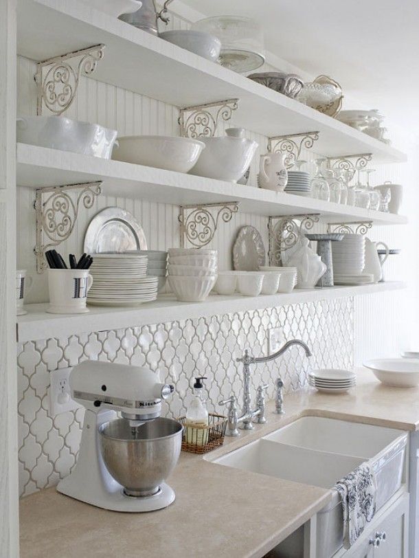 a beautiful white vintage kitchen with a chic tile backsplash, open shelving and beadboard and refined metal decorations