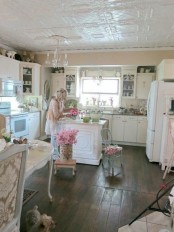 a neutral shabby chic kitchen with white cabinets, a crystal chandelier, a mini vintage kitchen island and touches of powder blue and pink