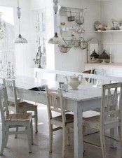 a neutral shabby chic kitchen with white cabinets, beadboard paneling, a shabby chic dining set in neutrals, vintage pendant lamps and vintage accessories