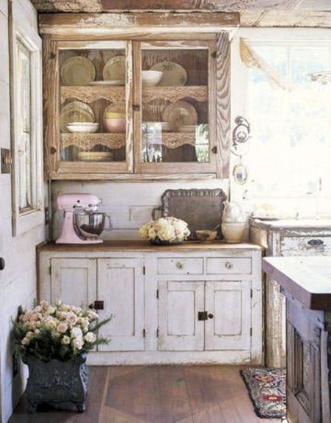 a rustic shabby chic kitchen with wooden cabinets, a dark stained kitchen island and stained floors and a large window