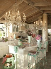 a vintage to shabby chic kitchen with white cabinets, a marble backsplash, crystal chandeliers and touches of mint and turquoise