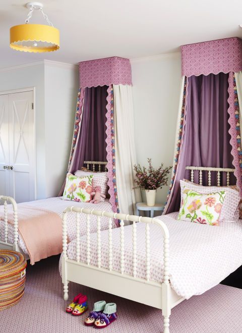 a chic and stylish shared girls' bedroom with white vintage beds, lilac and peachy bedding, purple canopies, a built in wardrobe and a woven basket for storage a chic and stylish shared girls' bedroom with white vintage beds, lilac and peachy bedding, purple canopies, a built-in wardrobe and a woven basket for storage