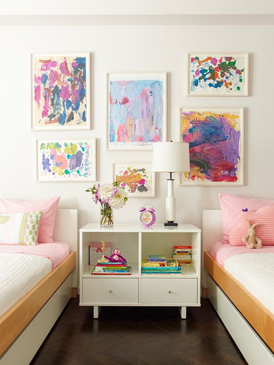 a pretty shared girls' bedroom with a bright watercolor gallery wall, sleek white beds with colorful bedding, a white nightstad and a white table lamp is wow a pretty shared girls' bedroom with a bright watercolor gallery wall, sleek white beds with colorful bedding, a white nightstad and a white table lamp is wow