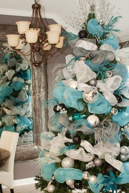 lush blue and silver Christmas tree decor with ribbons, ornaments, twigs, branches and beads is very formal and chic