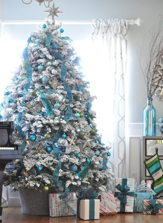a pretty blue and silver Christmas tree with ribbons, ornaments, some green touches and gifts under the tree is very refined and chic