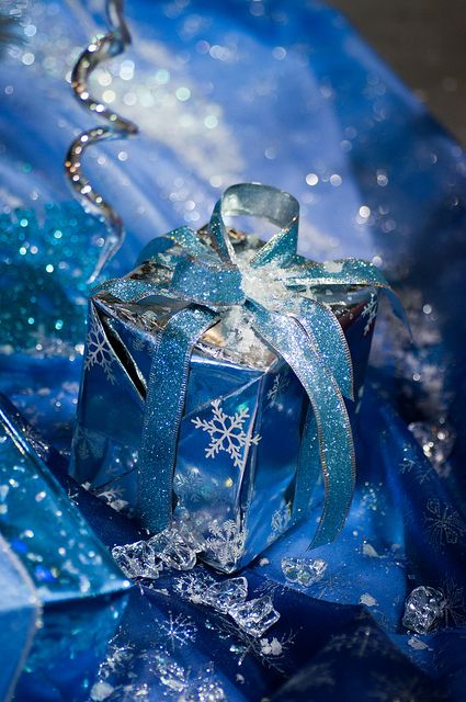 a Christmas gift wrapped in blue paper with snowflakes and with a large bow is a cool and bright idea to rock