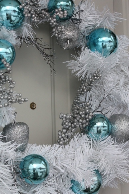 a white Christmas wreath with beads, silver and tiffany blue ornaments is a cool outdoor decoration to rock