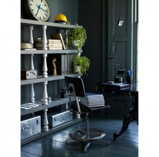a moody vintage home office with graphite grey shelves, a black desk and a vintage chair, potted greenery and a clock and carved pieces