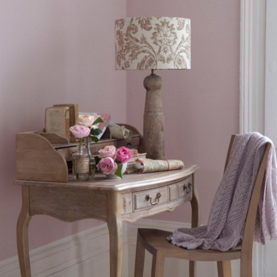 a delicate vintage home office with mauve walls, a stained carved vintage desk and a chair, a printed table lamp pink blooms