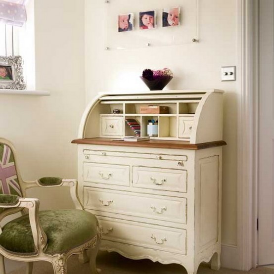 a neutral vintage home office nook with a vintage bureau desk, a vintage chair with green upholstery and a gallery wall