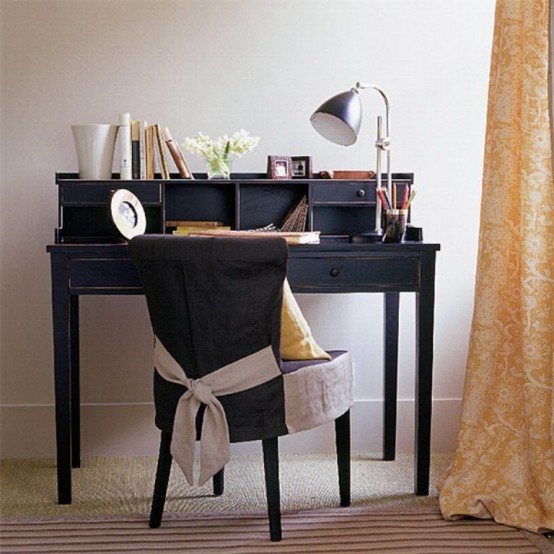 a vintage home office with a black vintage bureau desk, a black chair and table lamps and book, yellow printed curtains