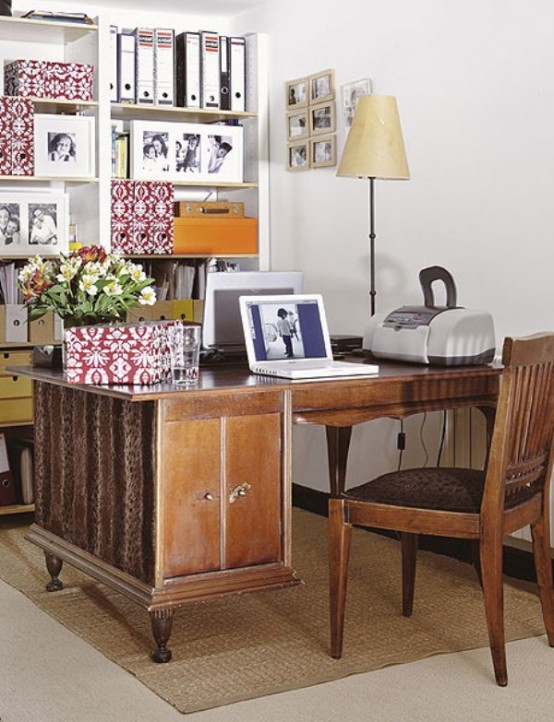 a vintage home office nook with a stained desk and a chair, a floor lamp and some printed files and books