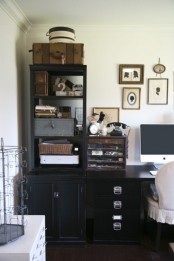 a vintage home office with black cabinets and a black shelving unit, a neutral vintage chair and a white sideboard, a vintage gallery wall
