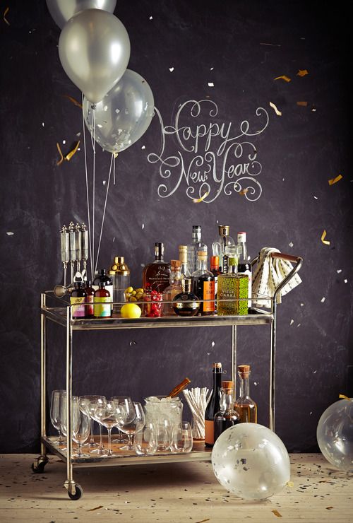 a NYE bar cart decorated with balloons and with a whole assortment of drinks and appetizers is a must for a NYE party