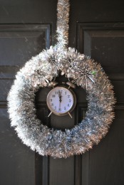 a silver tinsel NYE wreath with a silver vintage clock inside is a cool party decor idea that is easy to repeat