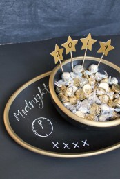 a couple of matte black plates with gold stars and candies to give them as party favors