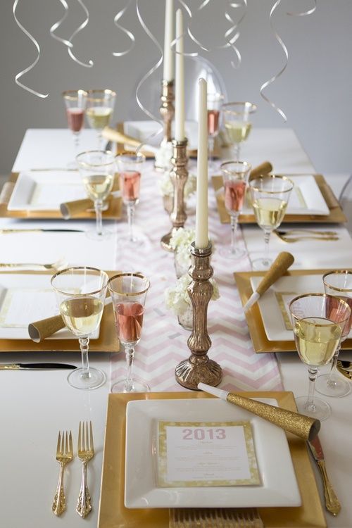 an elegant and glam NYE wedding tablescape with gold chargers and square plates, white blooms, candleholders with white candles and ribbons over the table