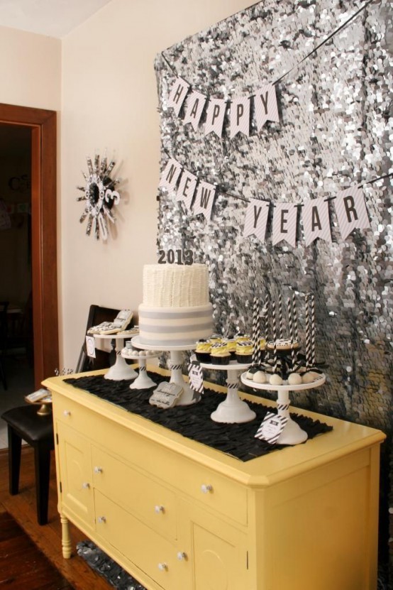 a silver sequin wall with banners is a lively and cool decor idea for a NYE party