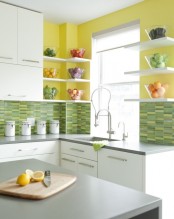 a stylish contemporary kitchen with yellow walls, green mosaic tiles, white cabinets and grey countertops rocks