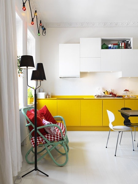 an eclectic kitchen with mustard lower cabinets and white uppers, with an aqua green bench and touches of black