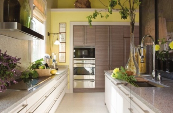 a modern ktichen with yellow walls, neutral cabinets, grey stone countertops and touches of real greenery for a fresh look