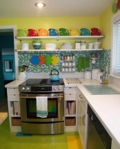 a colorful kitchen with a neon green floor, a green tile backsplash, a yellow wall and open shelves and bright tableware