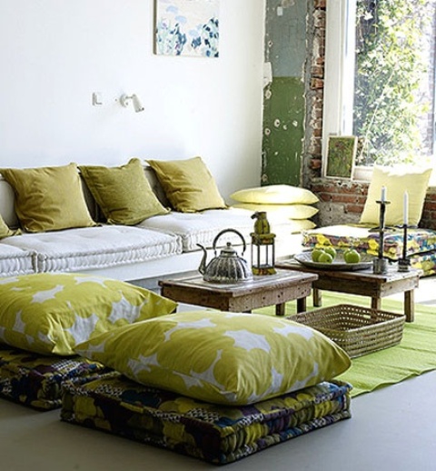 a summer living room in mustard shades, with lots of pillows and cushions and some fruits as additional decor