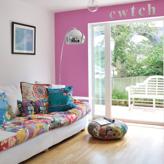 a hot pink wall, bright printed pillows and upholstery make the living room feel and look bright and summer-like
