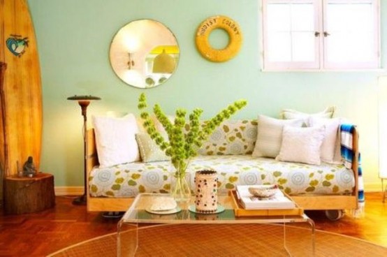 a colorful living room with mint walls, a botanical print sofa, an acrylic table, a mirror and some greenery in a vase