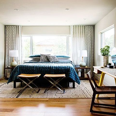 a stylish mid-century modern bedroom with a large bed, nighstands, desks and chairs plus much light