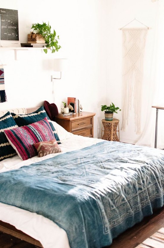 a boho meets mid-century modern bedroom with rich stained furniture, a macrame hanging and potted plants