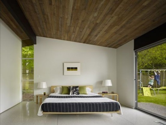 a very spacious and airy mid-century modern bedroom with a hairpin leg bed, simple stools as nightstands and windows to fill the space with light