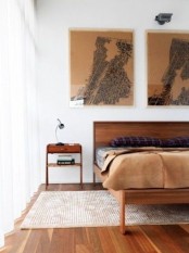a chic mid-century modern bedroom with rich stained furniture, artworks, a rug and moody bedding
