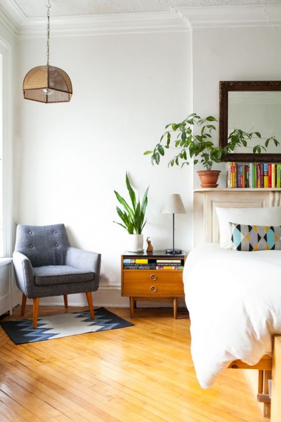 a mid-century modern bedroom with a bed, catchy nightstands, a grey chair and a suspended lamp