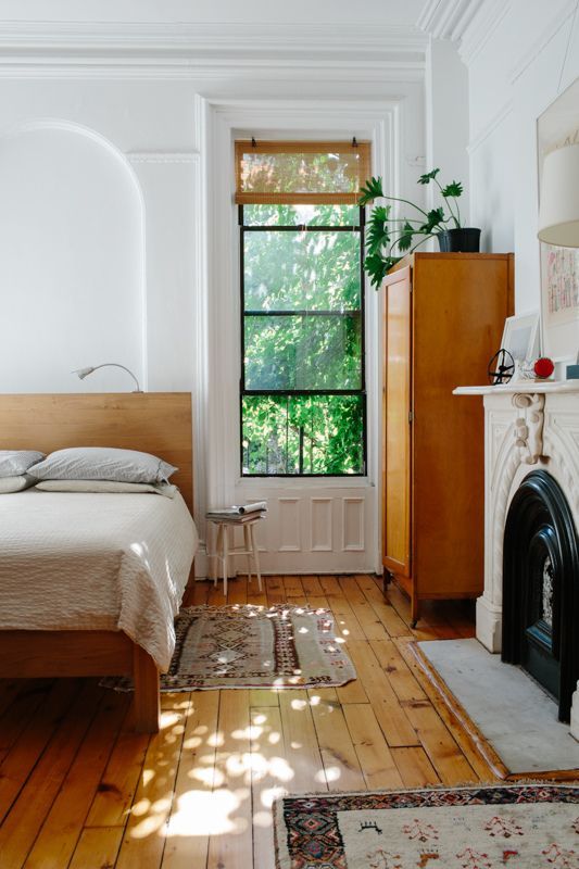 a mid-century modern meets rustic bedroom with light-colored wooden furniture, boho rugs and a fireplace