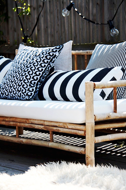 a rattan sofa with black and white pillows and cushions is a great solution for a black and white outdoor space, great for a Scandi interior