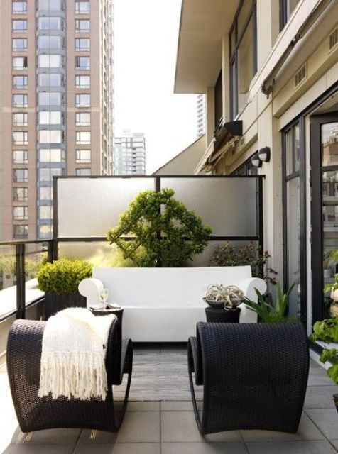 a sophisticated modern black and white space with a white sofa and black wicker chairs, with potted greenery and blooms