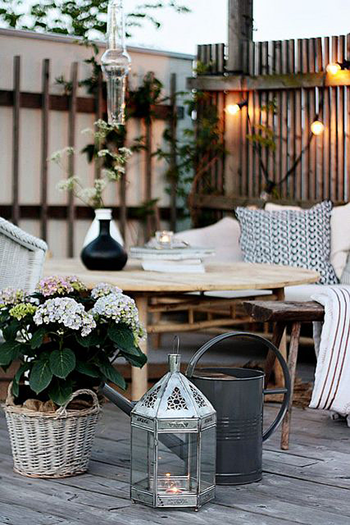 a Scandinavian terrace with rattan furniture, wicker chairs, potted plants and watering cans