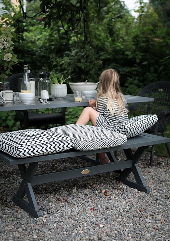 a stylish Scandinavian dining space with a black dining table and black benches, printed black and white cushions is a lovely idea with plenty of style