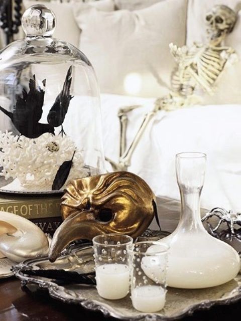 glam Halloween styling - candles in pearled candleholders, a gold mask, bats and a skeleton is a chic idea