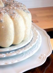 a white glitter pumpkin topped with pearls, beads and sequins is a very chic glam Halloween centerpiece or decoration