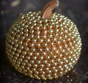 a pumpkin covered with gold beads is a chic and glam decoration you may rock at Halloween
