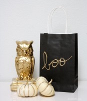 white pumpkins with gold stripes, a gold owl and a black paper bag with gold letters for a Halloween party