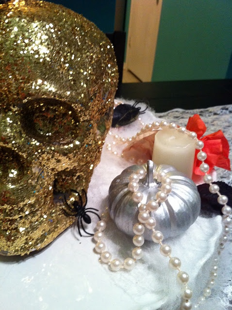 a gold glitter skull, a silver pumpkin, pearls and a candle for chic and shiny Halloween decor