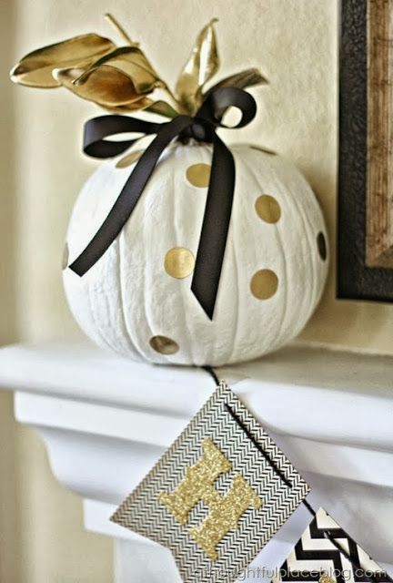 a white pumpkin with gold polka dots, a gold and blakc ribbon bow on top is a pretty Halloween decoration