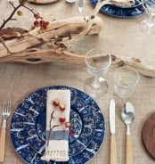 a fall Scandinavian tablescape with a burlap tablecloth, some driftwood with tiny apples and patterned plates