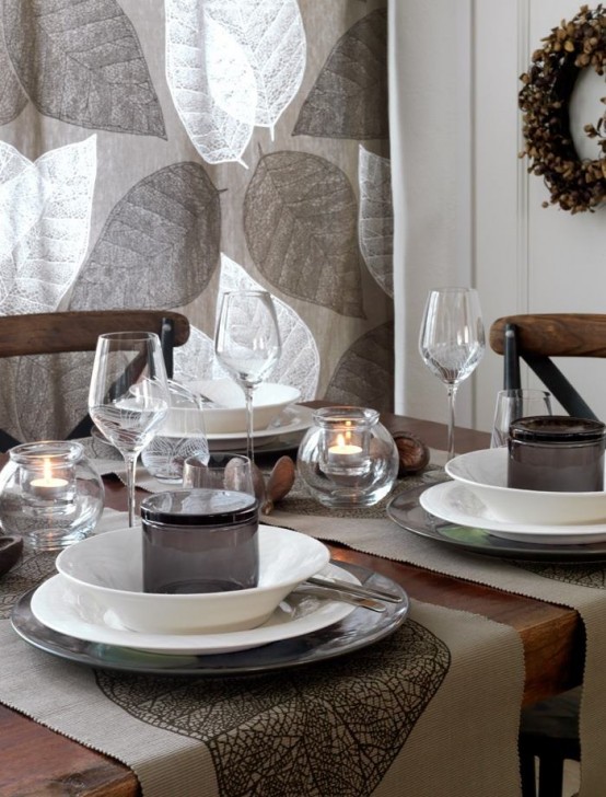 a Nordic fall tablescape made in greys, with a leafy curtain, candles, a wreath and some greyish textiles