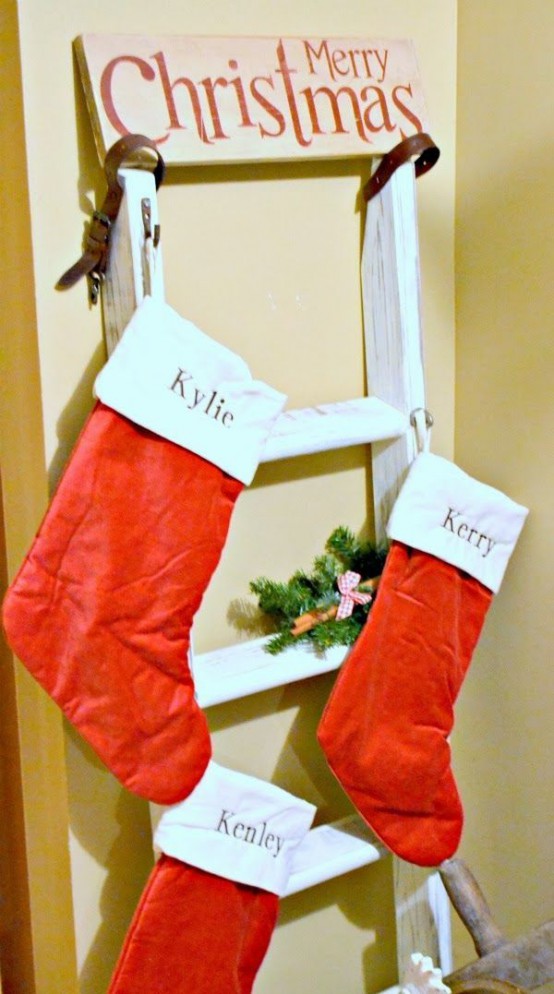 a ladder with classic red and white stockings and a sign on top is a simple and pretty rustic decoration for Christmas