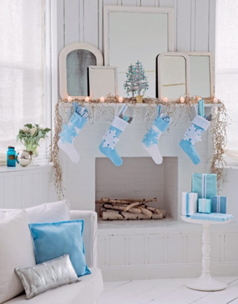 a pretty faux mantel with lights and blue and white stockings with snowflakes to match the decor of the space