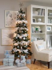 a Christmas tree with light blue, silver and white ornaments and white fluffy garlands plus a snowflake tree topper